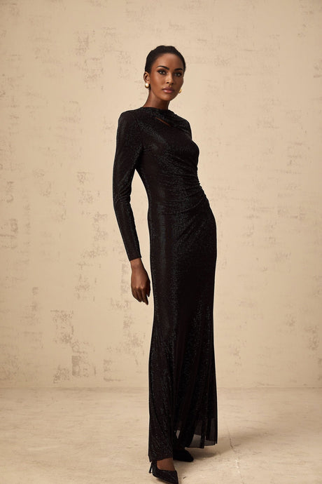 A long black maxi dress with ruched mesh fabric and rhinestone embellishments covering the bodice and sleeves