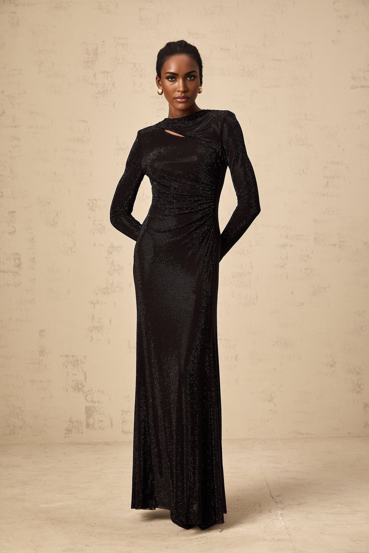 A long black maxi dress with ruched mesh fabric and rhinestone embellishments