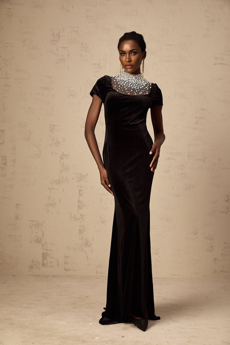 A long black velvet maxi dress with faux pearl embellishments on a mannequin or model