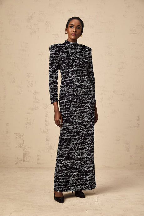 A long black velvet maxi dress with jade colored letter print design covering the fabric