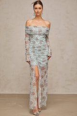 A long blue maxi dress with a floral print pattern and ruched detailing on a white background