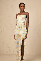 A long blue maxi dress with an asymmetric design featuring a floral print pattern and ruched detailing