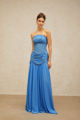 A long blue pleated maxi dress with faux pearl embellishments by Gaelle