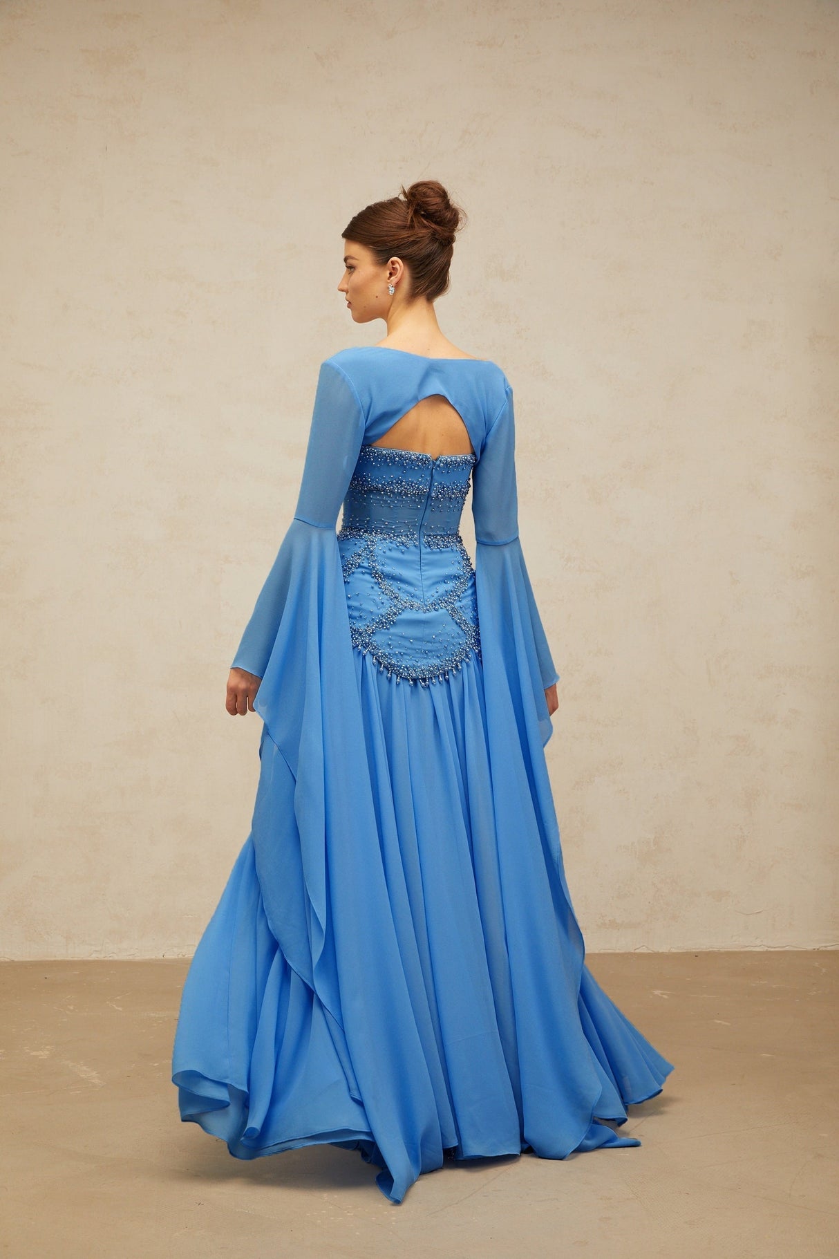A long blue pleated maxi dress with faux pearl embellishments by Gaelle