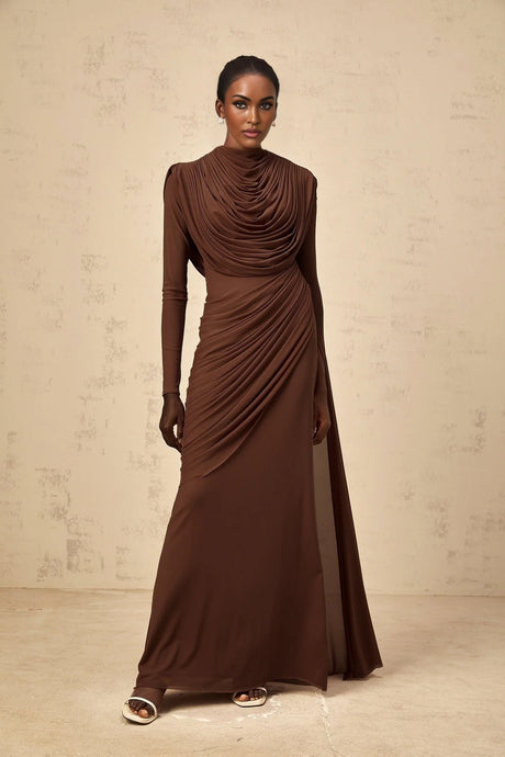 A long brown maxi dress with shirred detailing and draped fabric flowing to the floor