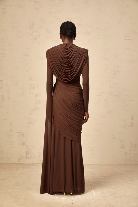 A long brown maxi dress with shirred detailing and draped fabric flowing to the floor