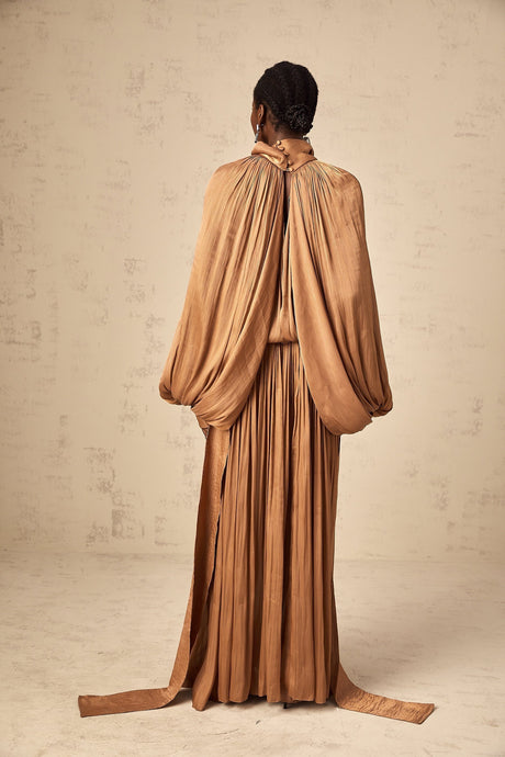 A long brown pleated satin maxi dress with a flowing silhouette and elegant drape