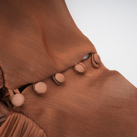 A long brown satin maxi dress with pleated details and a flowing silhouette