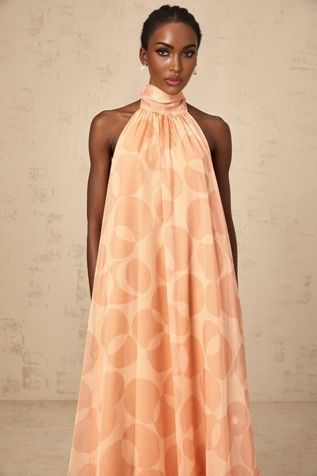 A long coralpink maxi dress with a halter neckline and allover pattern print