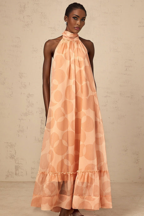 A long coralpink maxi dress with a halter neckline featuring an allover pattern print and a flowing silhouette