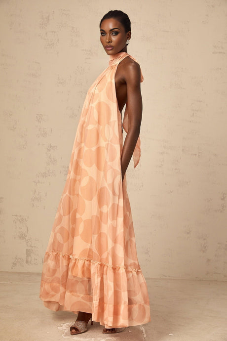 A long coralpink maxi dress with a halter neckline featuring an allover pattern print