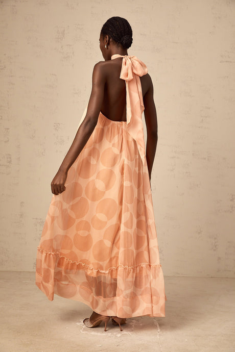 A long coralpink maxi dress with a halter neckline featuring an allover pattern print