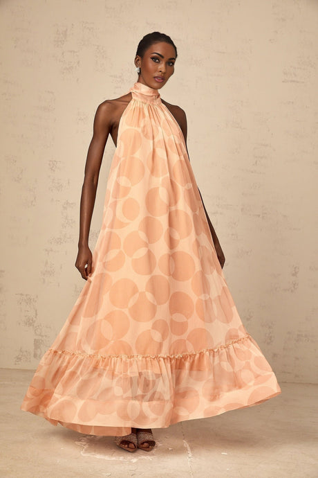 A long coralpink maxi dress with a halter neckline featuring an allover pattern print
