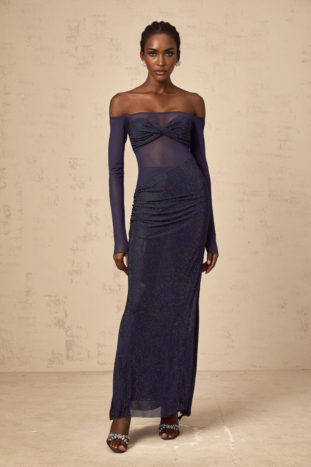 A long dark blue maxi dress with a corsetstyle bodice featuring sheer tulle panels and embellished details
