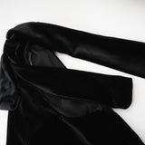 A long dark velvet dress with an open back and embellished details named Audrey shown on a model against a plain background