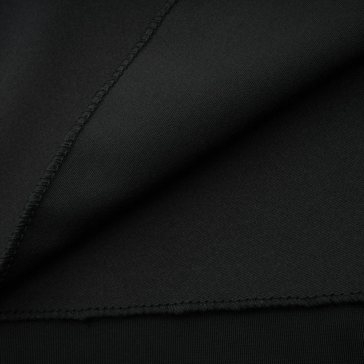 A long dark velvet dress with an open back and embellished details worn by a model standing in an elegant pose