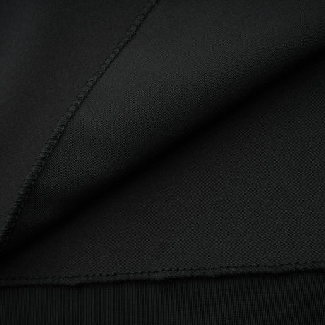 A long dark velvet dress with an open back and embellished details worn by a model standing in an elegant pose