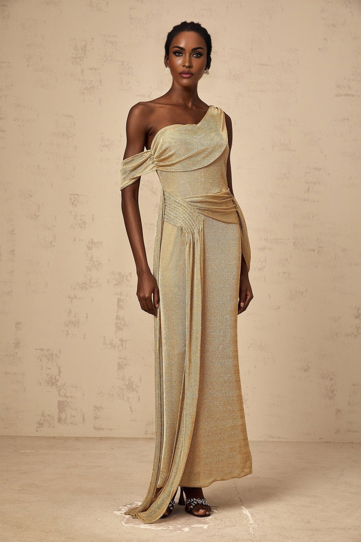 A long elegant gold maxi dress with ribbon design details and gathered fabric featuring a flowy silhouette