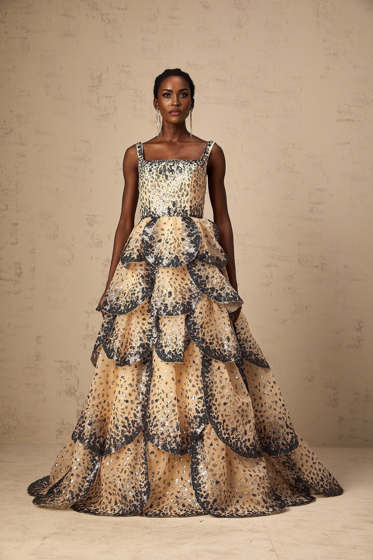A long elegant maxi dress with tiered layers featuring shimmering sequin details and a delicate petal design throughout