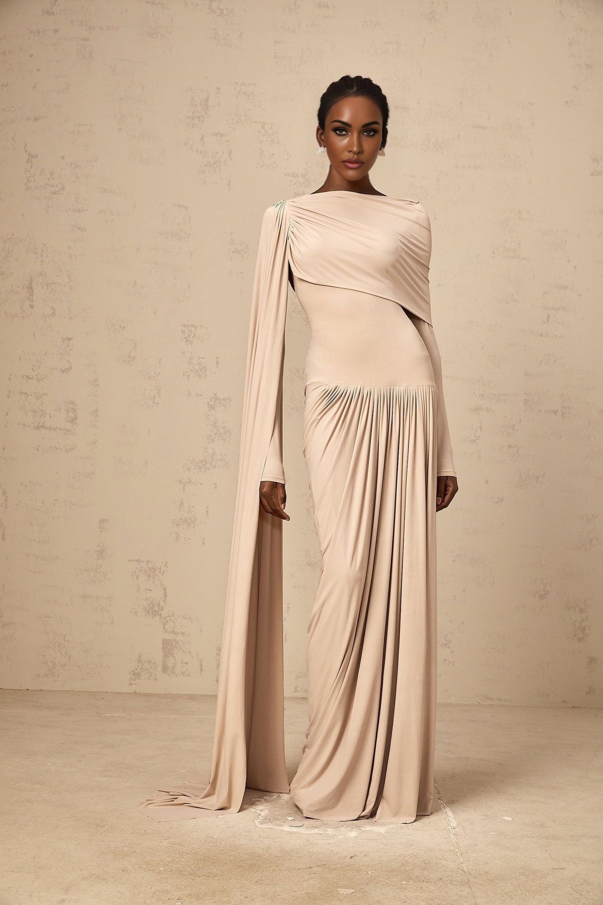 A long flowing maxi dress in neutral tones featuring a draped design with ribbon details