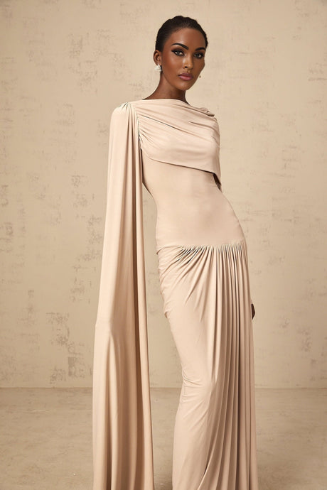 A long flowing maxi dress in neutral tones featuring a ribbon design and draped silhouette