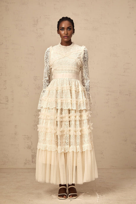 A long flowing maxi dress in neutral tones featuring lace panels and ruffled tulle details