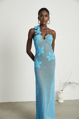 A long flowing maxi dress with intricate crochet detailing and colorful faux flower embellishments