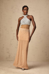 A long flowy maxi dress in a light color with sheer fabric and pearl decorations throughout