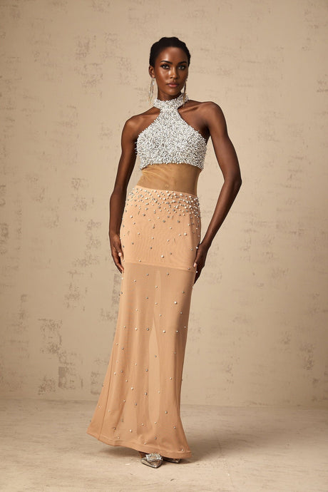 A long flowy maxi dress in a light color with sheer fabric and pearl decorations throughout