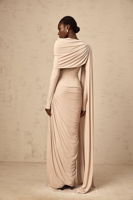 A long flowy maxi dress in neutral tones featuring a draped design and ribbon details