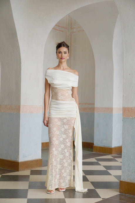 A long flowy maxi dress in neutral tones featuring floral lace panels and ribbon details with a feminine silhouette
