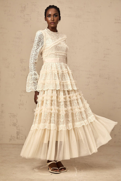 A long flowy maxi dress in neutral tones with lace panels and ruffle details made from tulle fabric