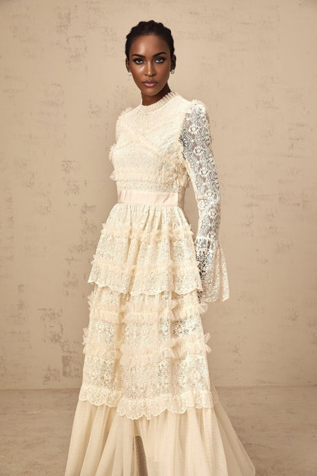 A long flowy maxi dress in neutral tones with lace panels and ruffled tulle details