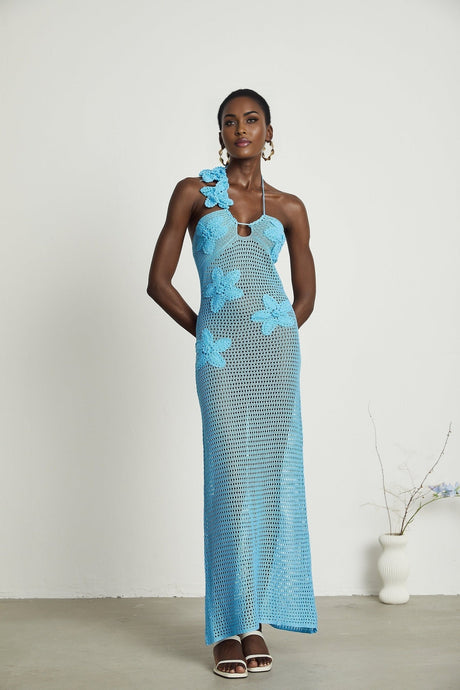 A long flowy maxi dress with crochet detailing and decorative faux flowers throughout the design
