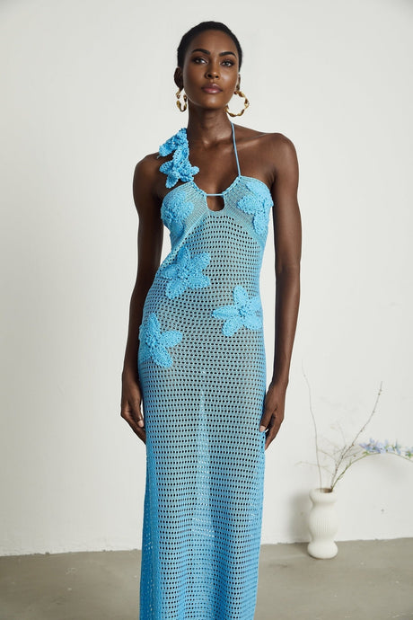 A long flowy maxi dress with crochet details and decorative faux flowers scattered throughout the design