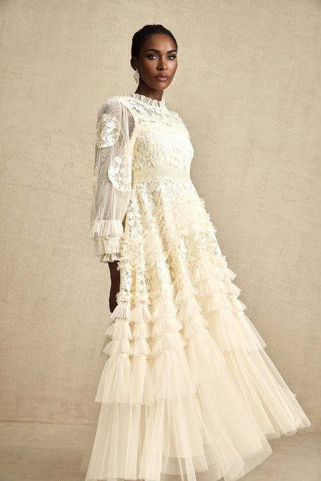 A long flowy maxi dress with multiple layers of sheer tulle fabric featuring delicate floral embroidery in a Capucine style