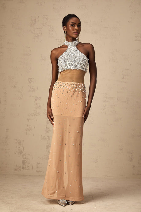 A long flowy white maxi dress with sheer elements adorned with small faux pearl embellishments throughout