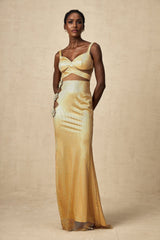 A long gold maxi dress with floral cutout details and a flowing silhouette