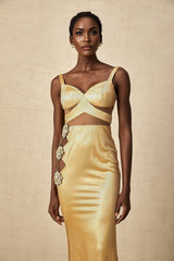 A long gold maxi dress with floral cutout details and a flowing silhouette