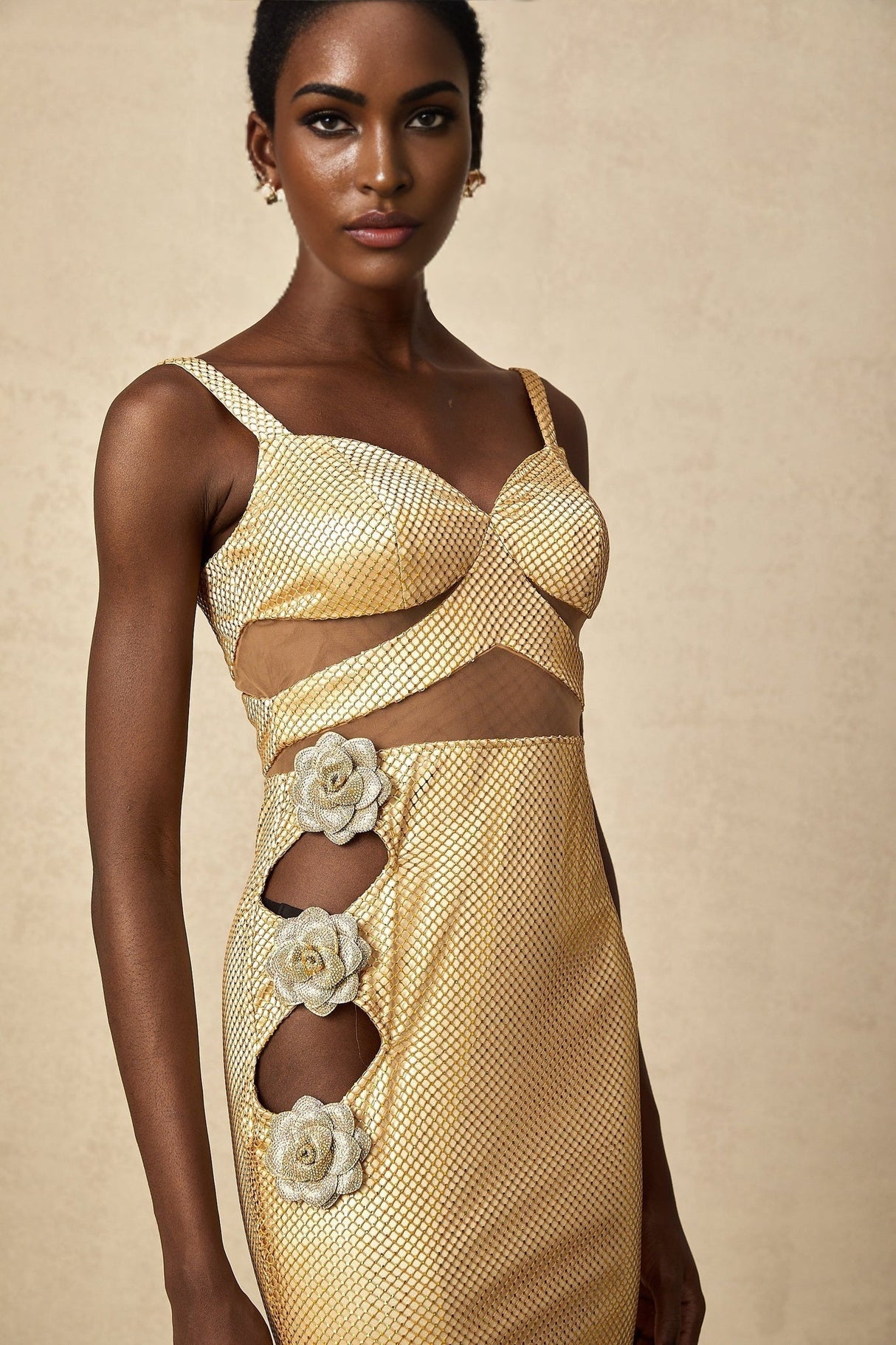 A long gold maxi dress with floral cutout details and a sleek silhouette suitable for formal occasions
