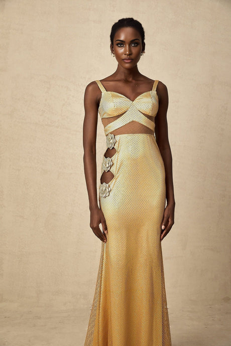 A long gold maxi dress with floral cutout patterns worn by a model standing against a plain background