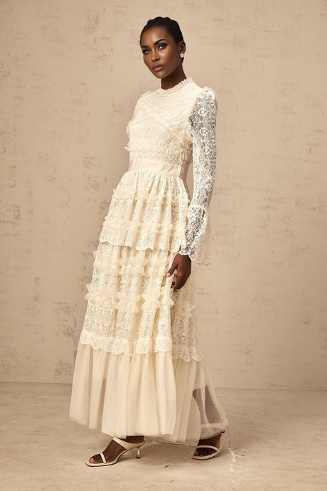 A long neutral colored maxi dress with lace panels and ruffled tulle details