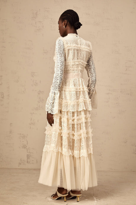 A long neutral colored tulle maxi dress with lace panels and ruffled details featuring a feminine silhouette and delicate design elements