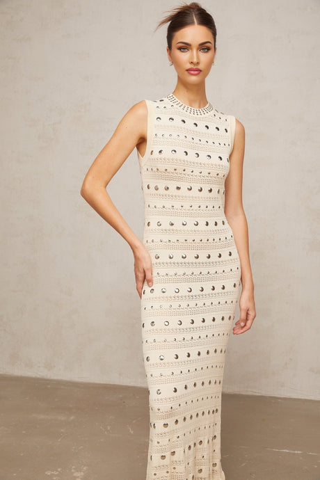 A long neutralcolored maxi dress with crochetknit pattern and studded details designed by Chloé
