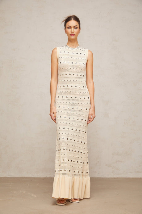 A long neutralcolored maxi dress with crochetknit pattern and studded details made by Chloé