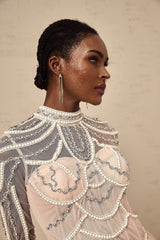 A long pink gown with tiered layers of sheer fabric and beaded detailing worn by a model
