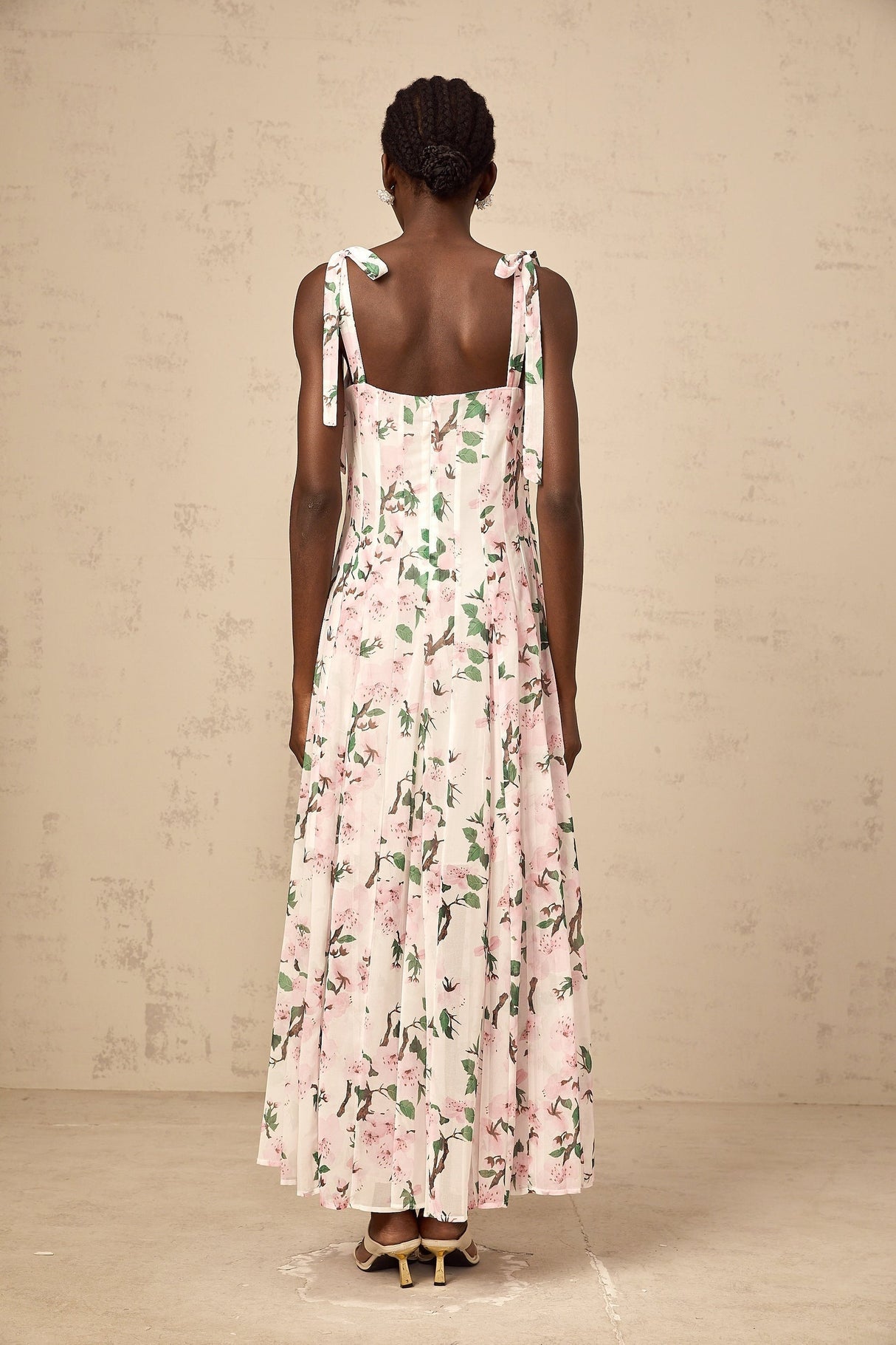A long pink maxi dress with a floral print pattern and thin tied straps