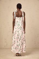 A long pink maxi dress with a floral print pattern and thin tied straps