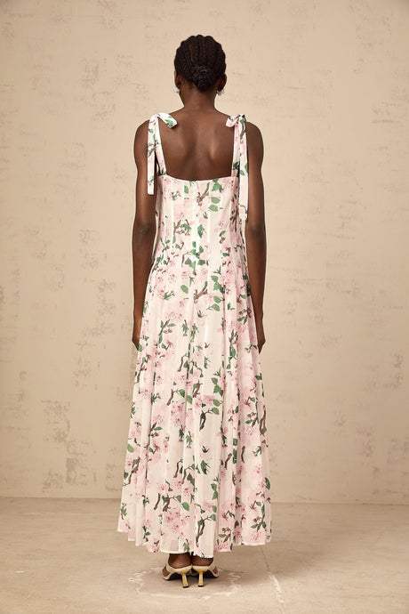 A long pink maxi dress with a floral print pattern and thin tied straps