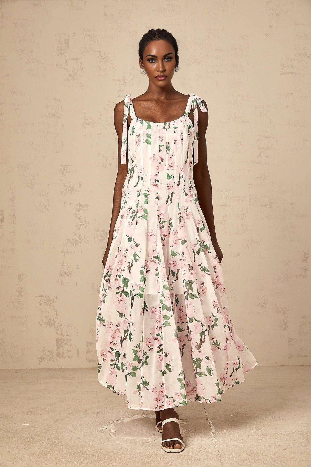 A long pink maxi dress with a floral print pattern and tied straps